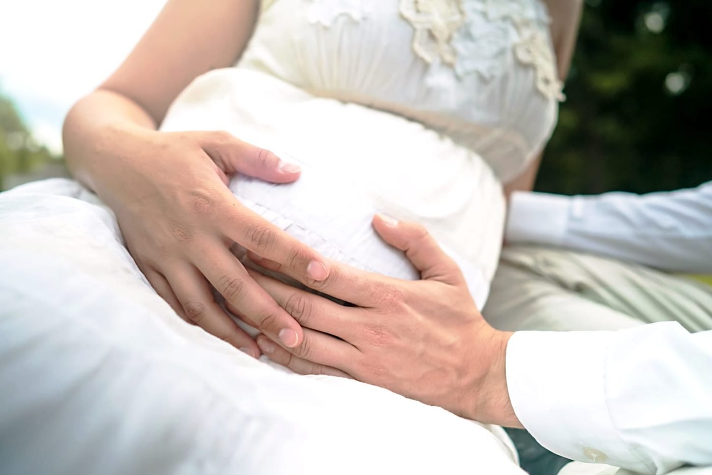 Werdende Eltern legen gemeinsam die Hände auf den Babybauch