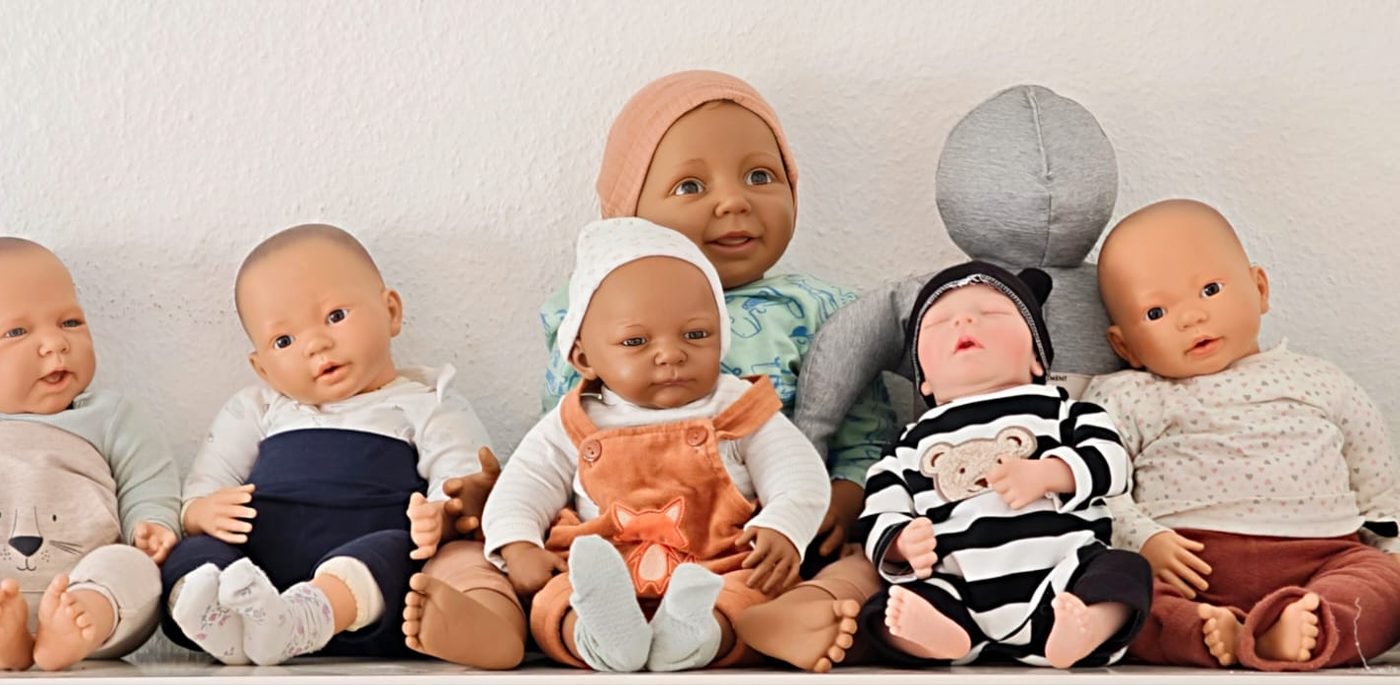 Sieben Tragepuppen sitzen nebeneinander und warten auf den Workshop